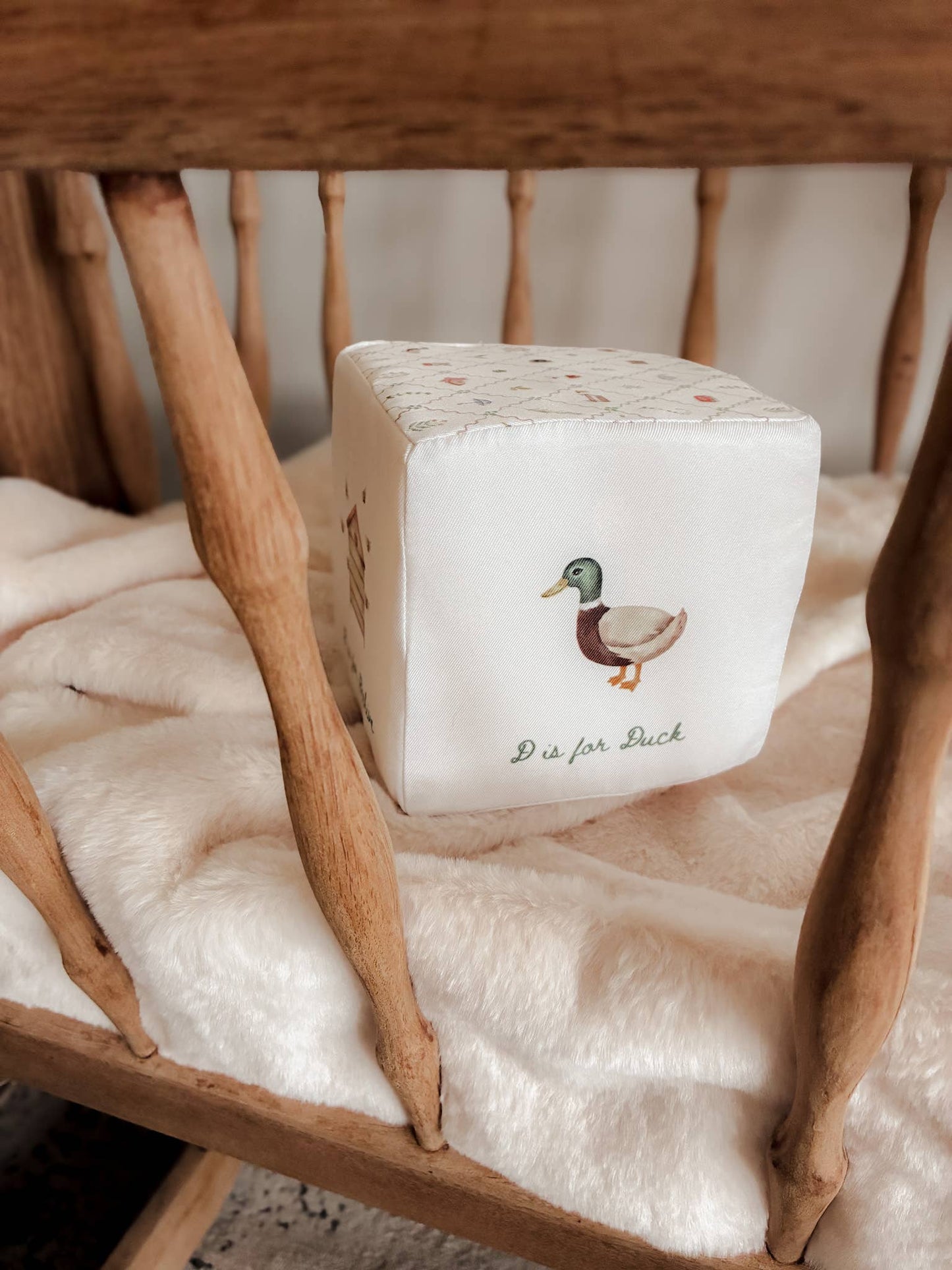 White cube with a duck illustration on a wooden chair