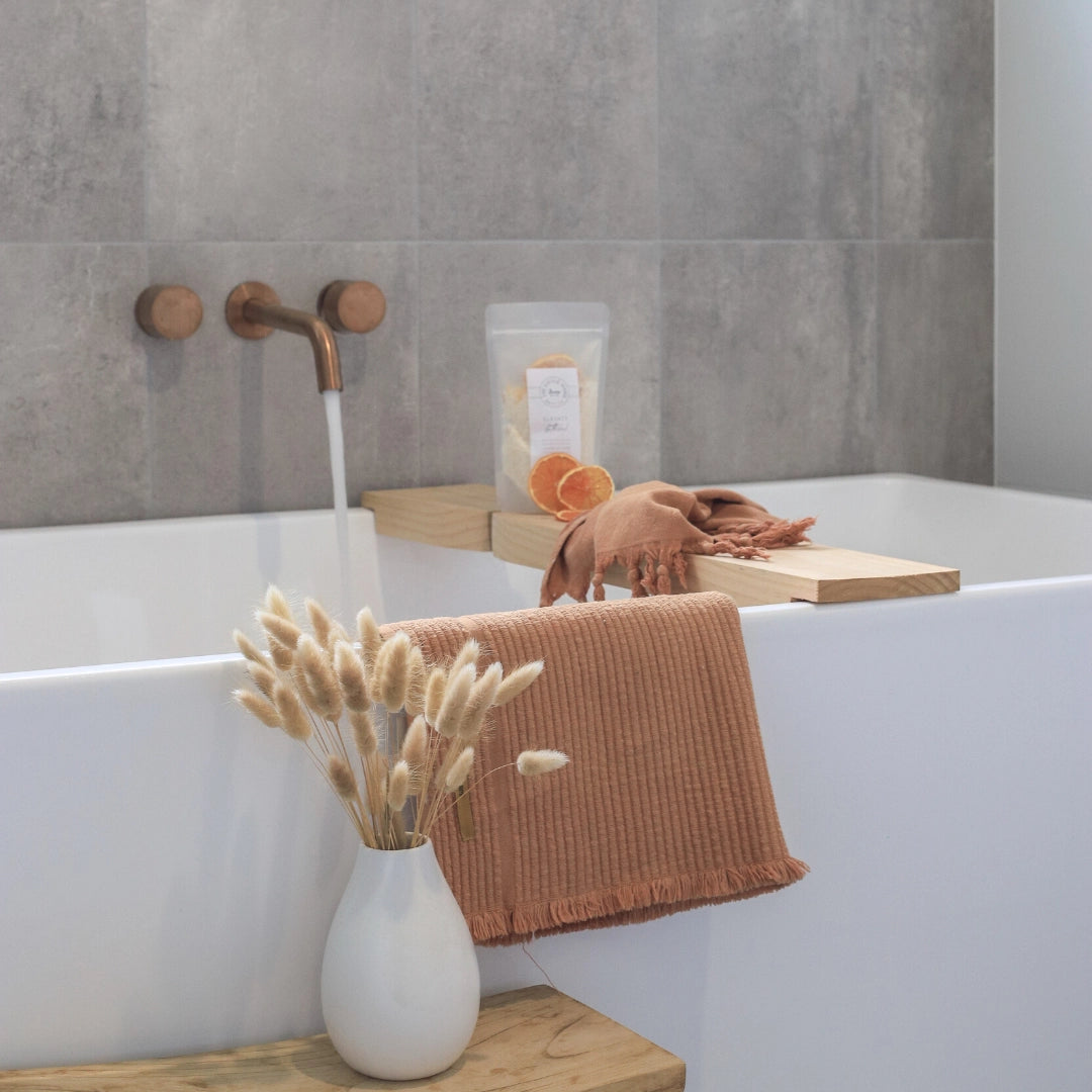 Bathroom scene with a bathtub, towel, and decorative elements.
