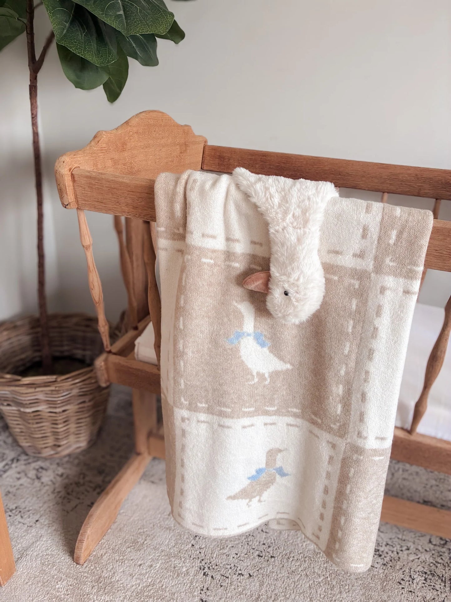 Baby blanket with animal patterns draped over a wooden chair
