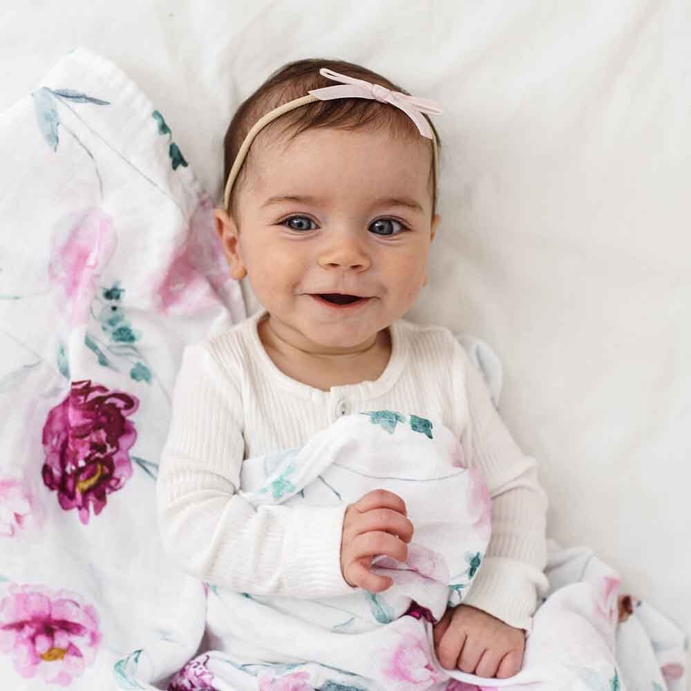 Baby lying on a floral blanket with a pink headband
