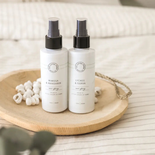 Two white spray bottles with black caps on a wooden tray.