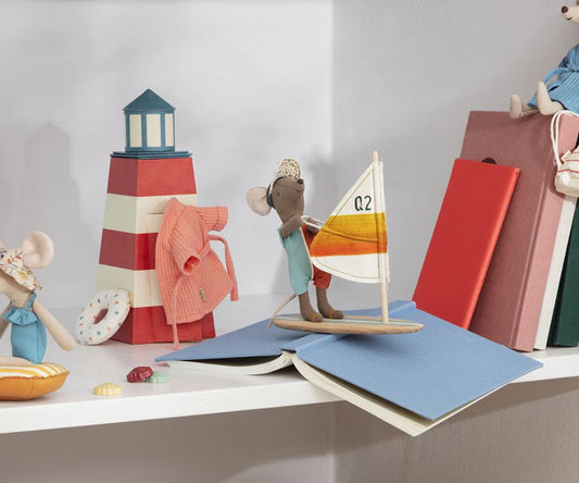 Toy mouse with a sailboat and lighthouse on books against a white background