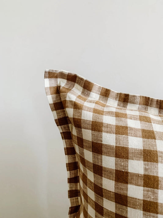 Brown and white checkered pillow on a light gray background