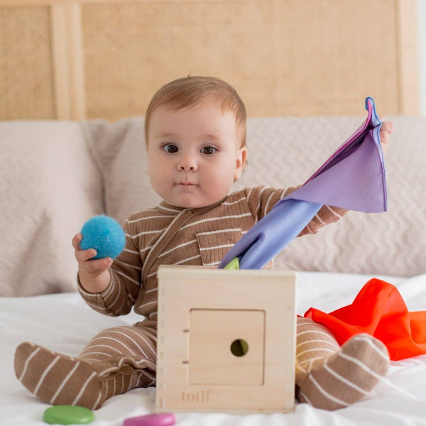 Baby playing with colorful toys on a bed