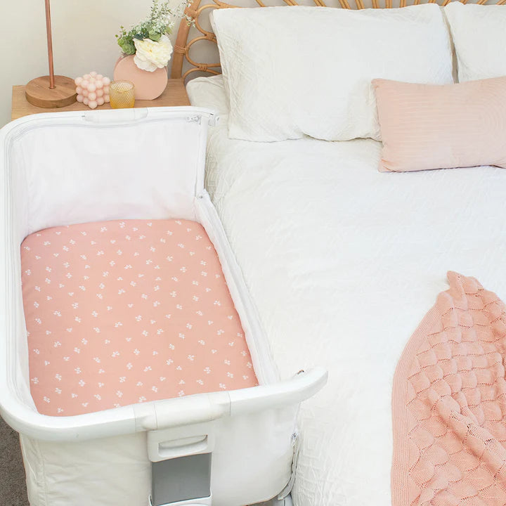 Baby crib with pink mattress in a bedroom setting