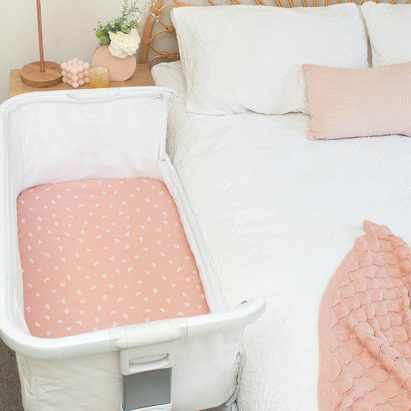 Baby crib with pink mattress in a bedroom setting