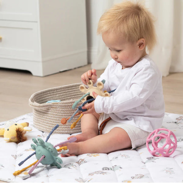 Baby playing with toys on a bed in a nursery setting