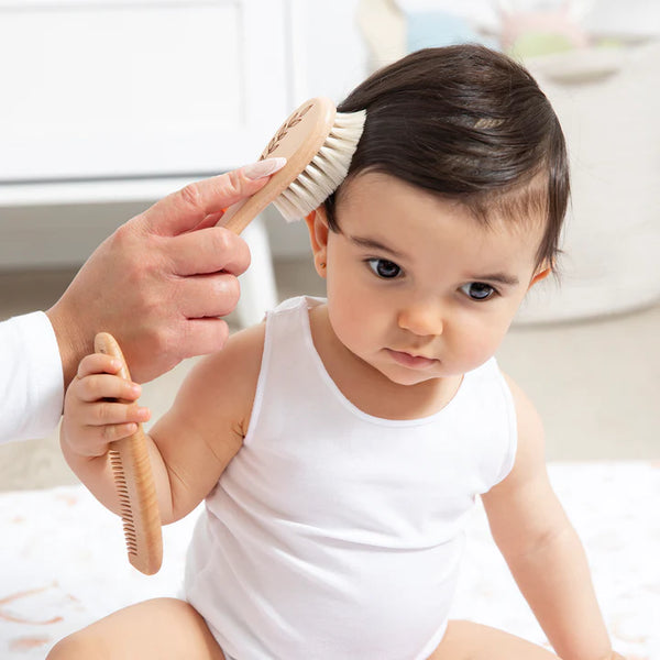 Baby being groomed with a brush by an adult in a home setting