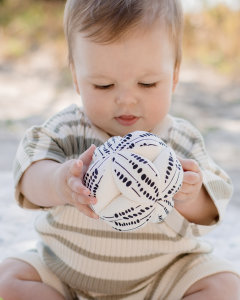 Child holding a patterned ball outdoors