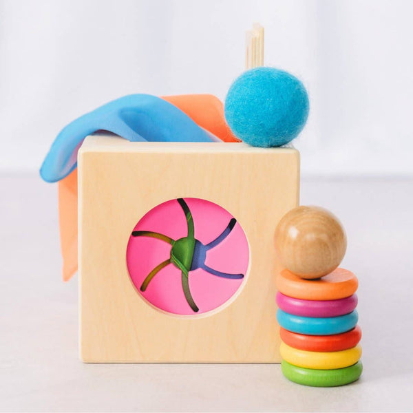 Colorful wooden toy set with geometric shapes and a stack of rings on a light background