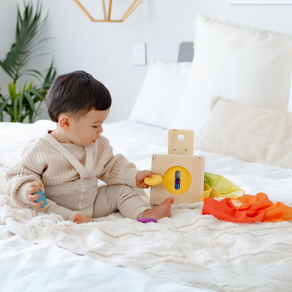 Child playing with educational toys on a bed in a bright room