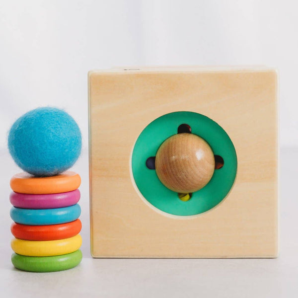 Colorful stack of rings and wooden toy with circular cutout on a white background