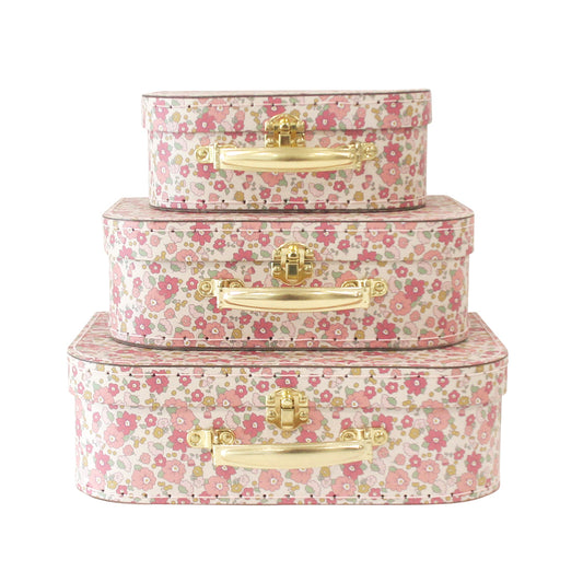Set of three floral-patterned suitcases with gold handles on a white background