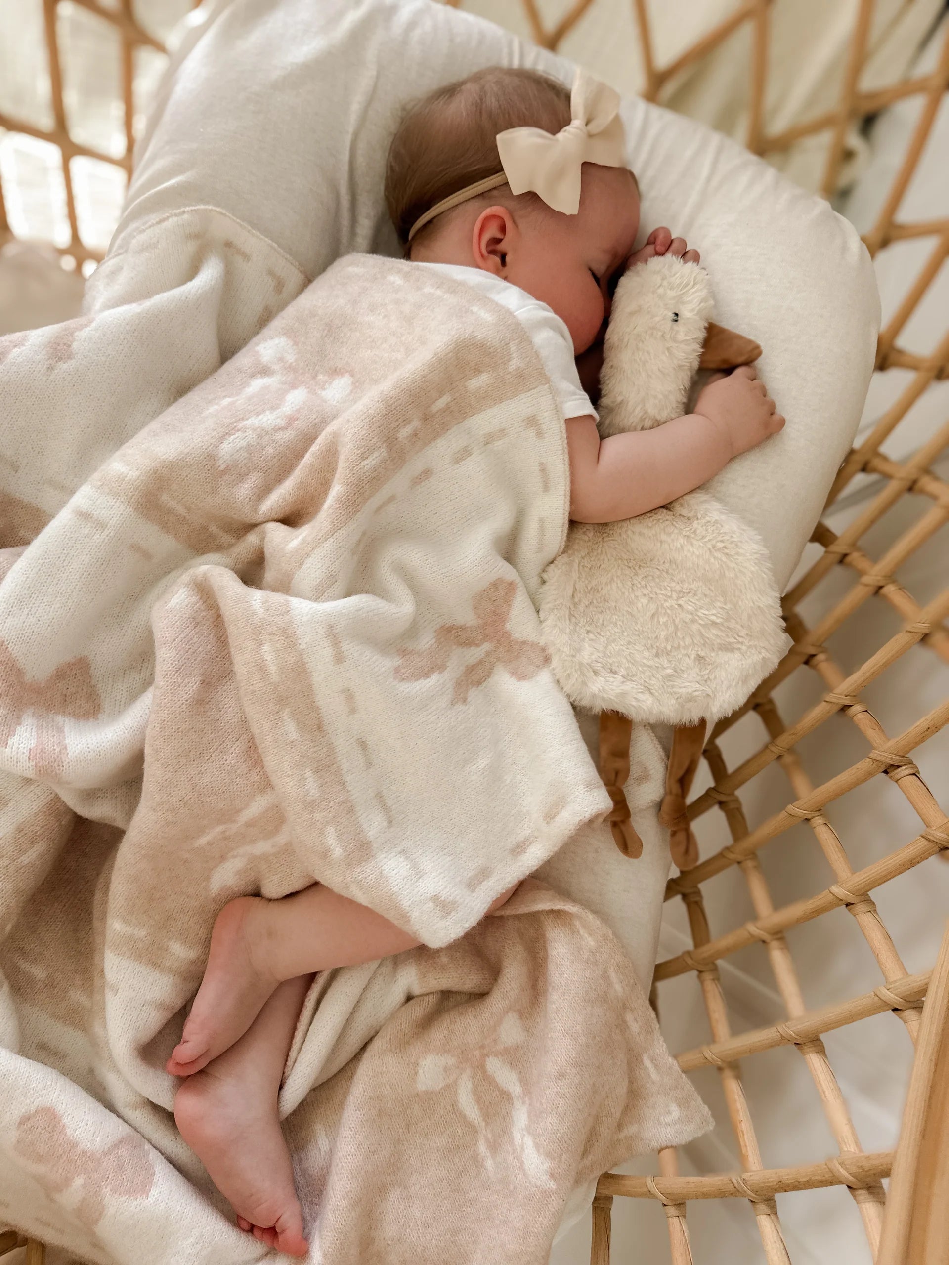 Baby sleeping in a crib with a soft blanket and plush toy