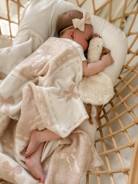 Baby sleeping in a crib with a soft blanket and plush toy