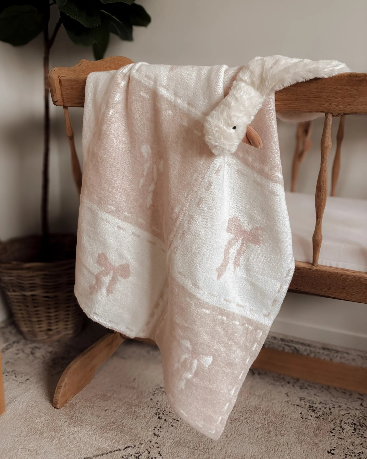 White lace baby blanket draped over a wooden chair with a plant in the background