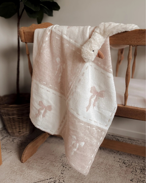 White lace baby blanket draped over a wooden chair with a plant in the background