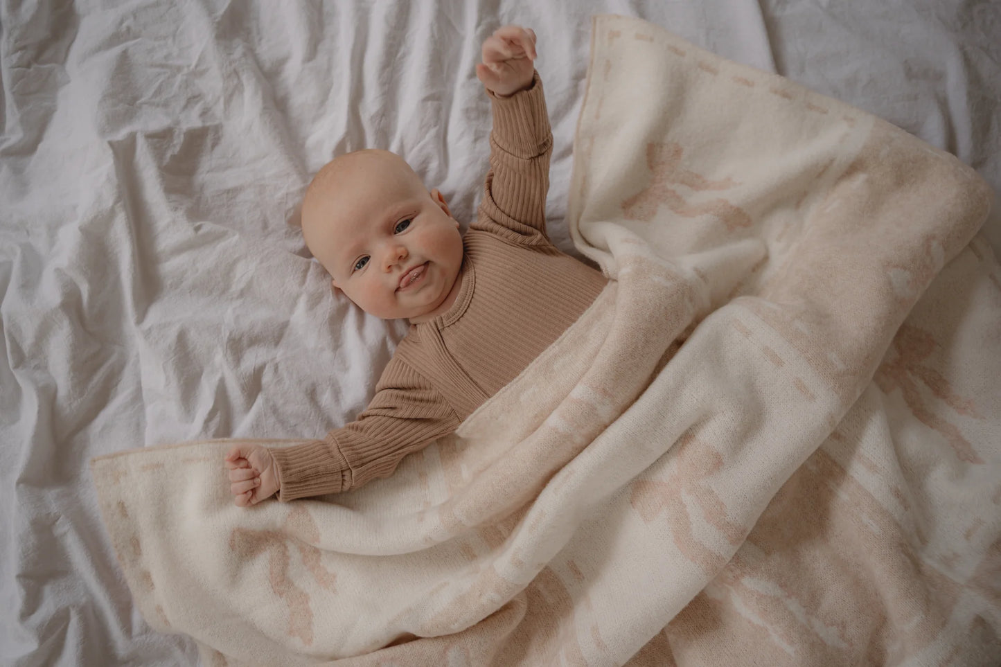 Baby in a brown outfit lying on a textured blanket
