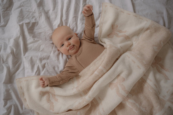 Baby in a brown outfit lying on a textured blanket