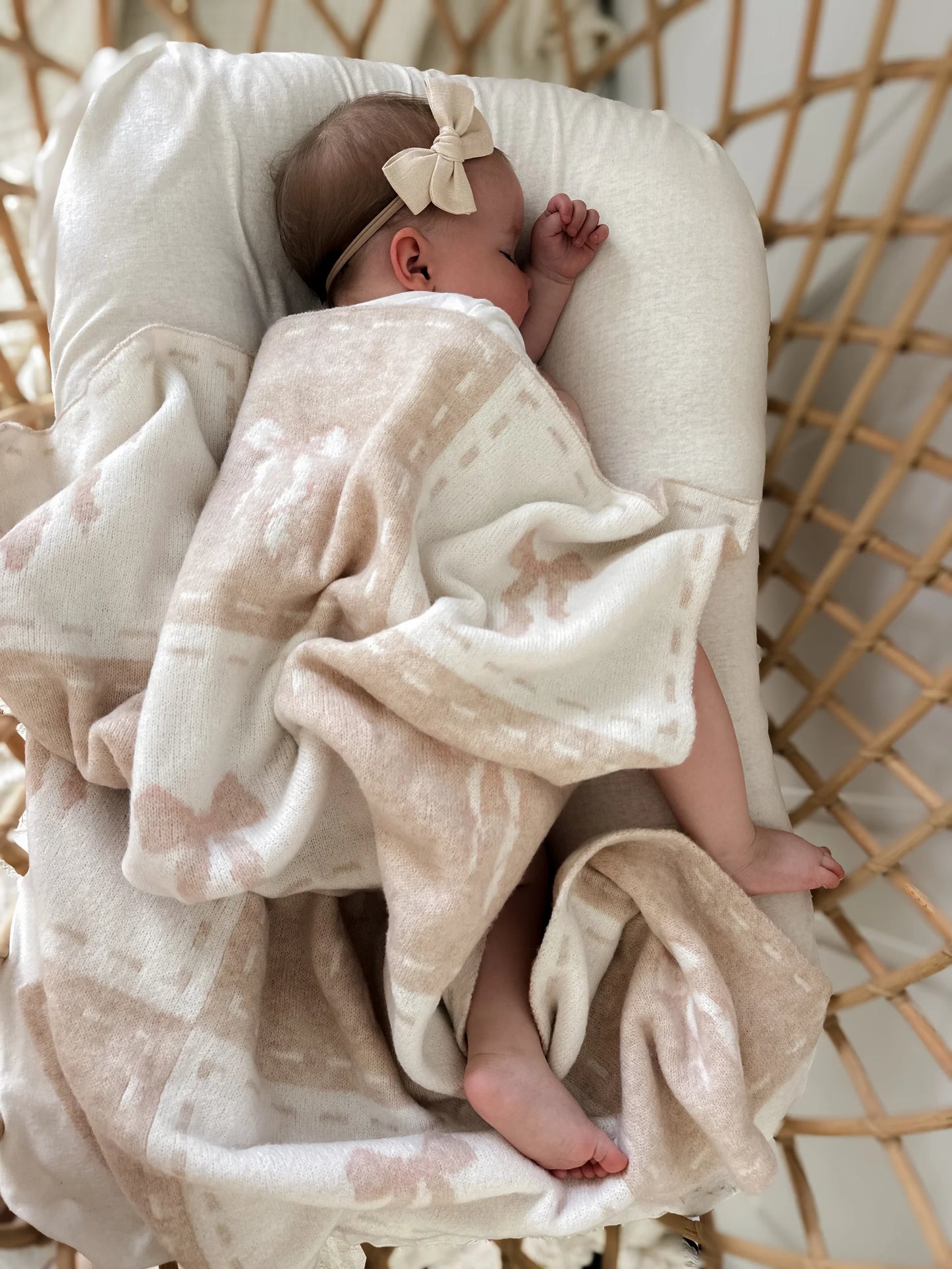 Baby wrapped in a blanket with a bow, lying on a textured surface