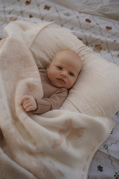 Baby lying on a pillow under a blanket with butterfly patterns