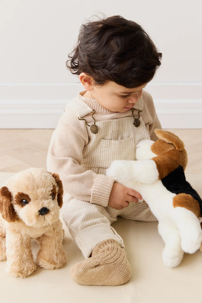 Child playing with plush toys on a light-colored surface. Snuggle Bunnies - Brooklyn The Beagle
