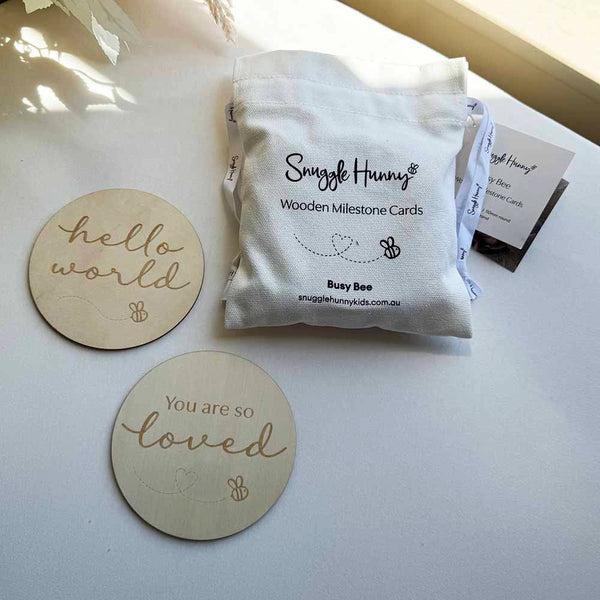 Snuggle Hunny wooden milestone cards packaging with two engraved wooden discs on a light surface.