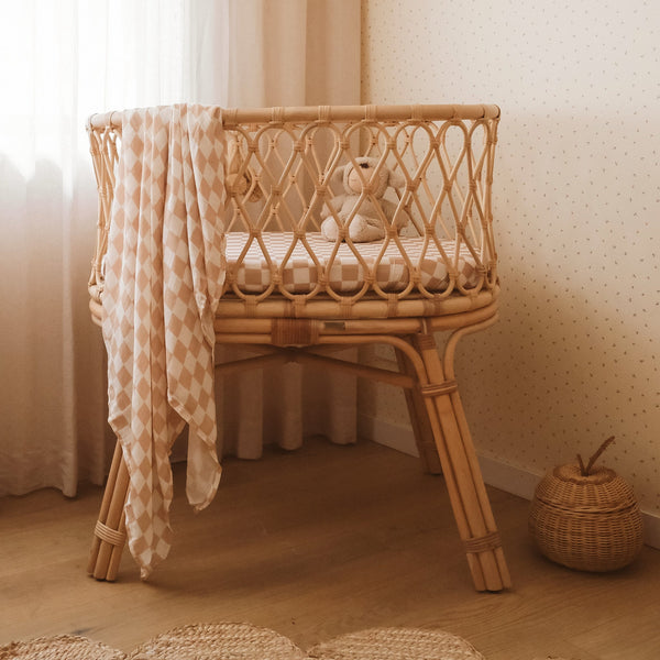 Wicker crib with a checkered blanket in a softly lit room