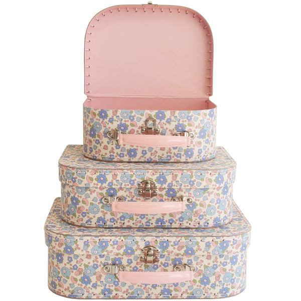 Set of three floral-patterned suitcases with pink accents on a white background