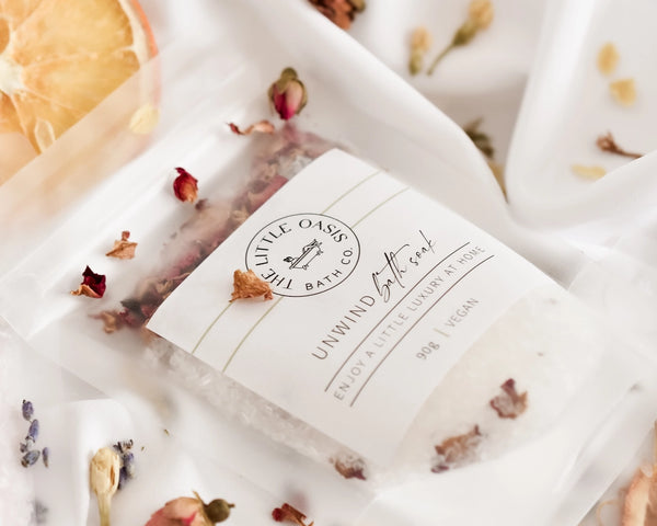 Bar of soap with 'Little Oasis Bath Co' branding on a white background with dried flowers.