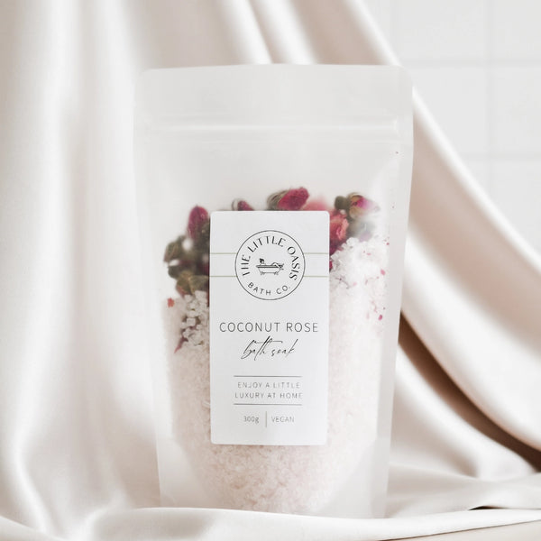Coconut Rose bath salt package with a label on a white fabric background