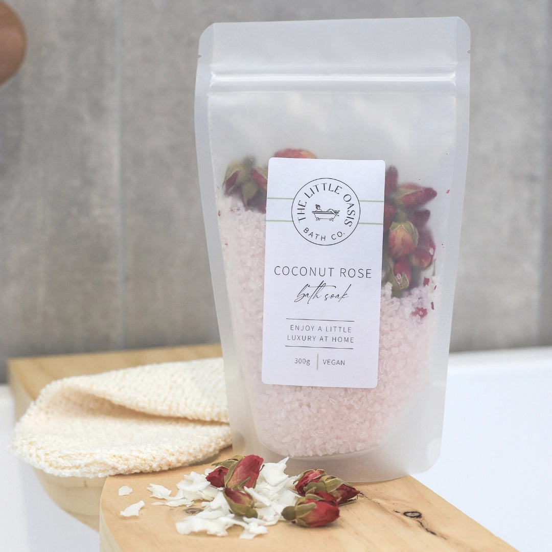 Bag of coconut rose bath soak with a label on a wooden board.