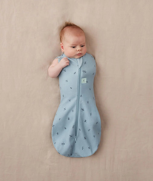 Baby in a blue sleeping bag with a pattern on a beige background