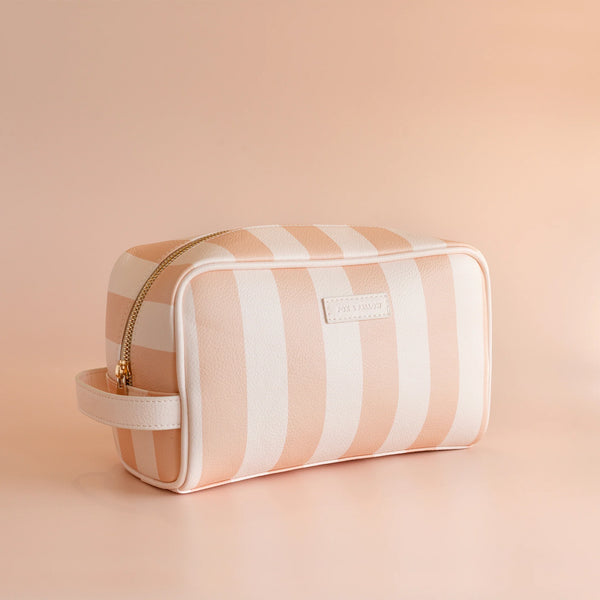 Striped toiletry bag with gold zipper on a beige background