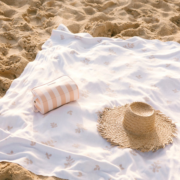 Beach towel with a hat and striped bag on sand