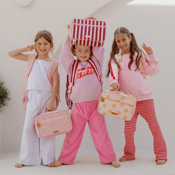 Three children in pajamas holding bags against a white background