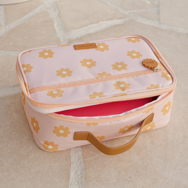 Pink lunch bag with floral pattern on a beige floor