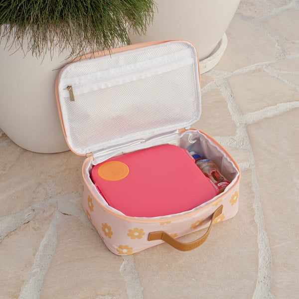 Pink and orange item in a floral-patterned lunch bag on a stone surface.