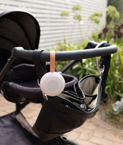 White baby monitor attached to a stroller with a blurred outdoor background