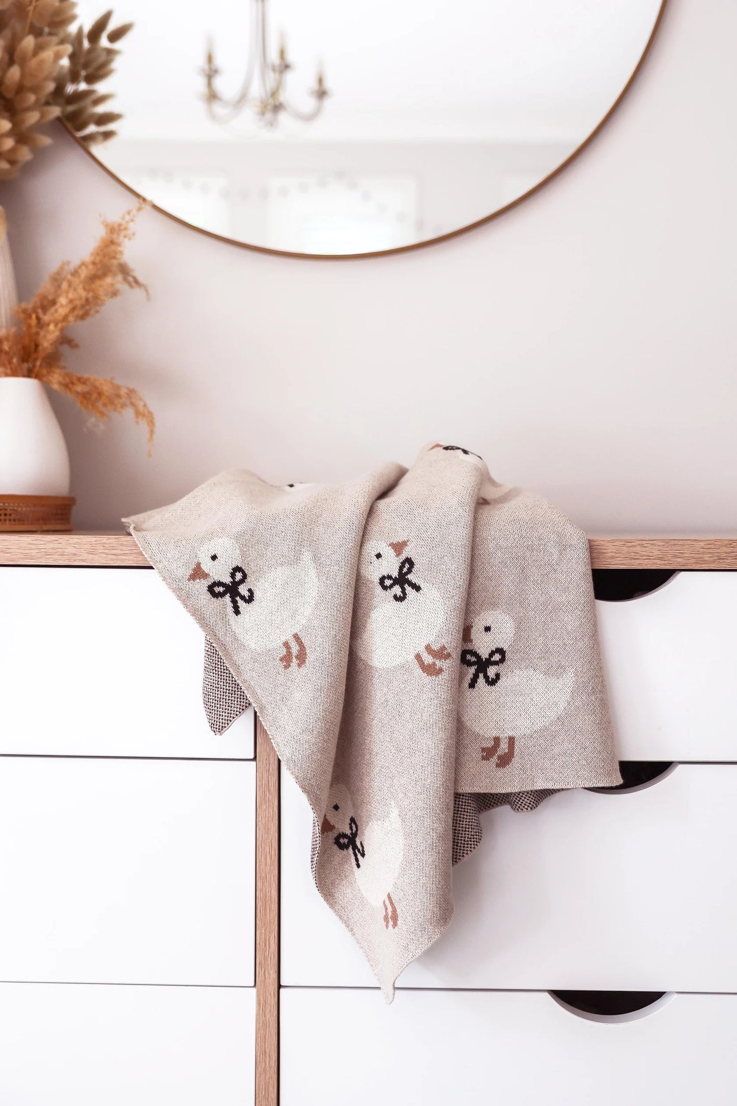 Decorative towel with duck patterns hanging on a wooden rack against a white wall.