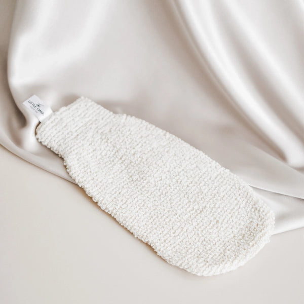 White textured bath mitt on a beige fabric background