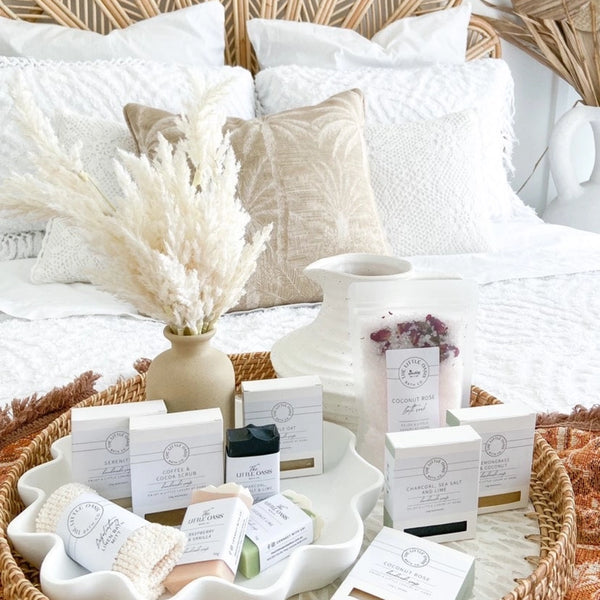 Collection of skincare products on a bed with decorative pillows and decor.