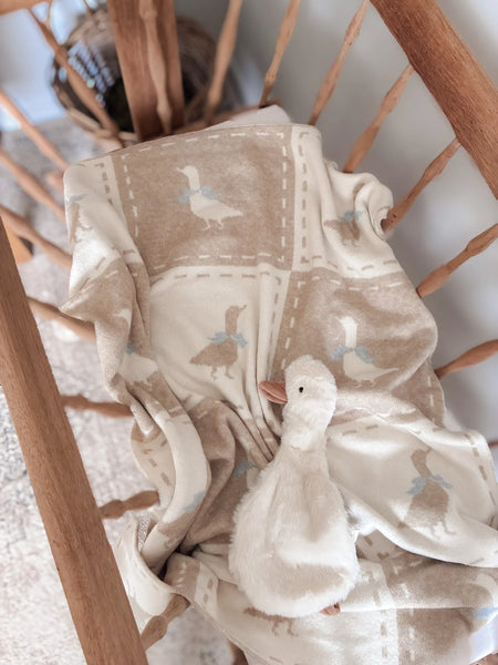 Baby blanket with duck pattern draped over a wooden chair