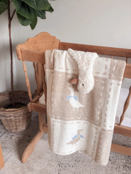 Baby blanket with animal patterns draped over a wooden chair