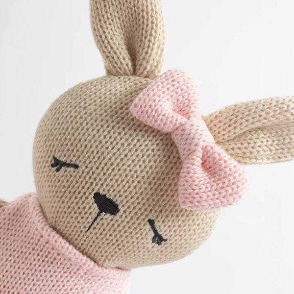 Knitted bunny toy with pink bow on a white background