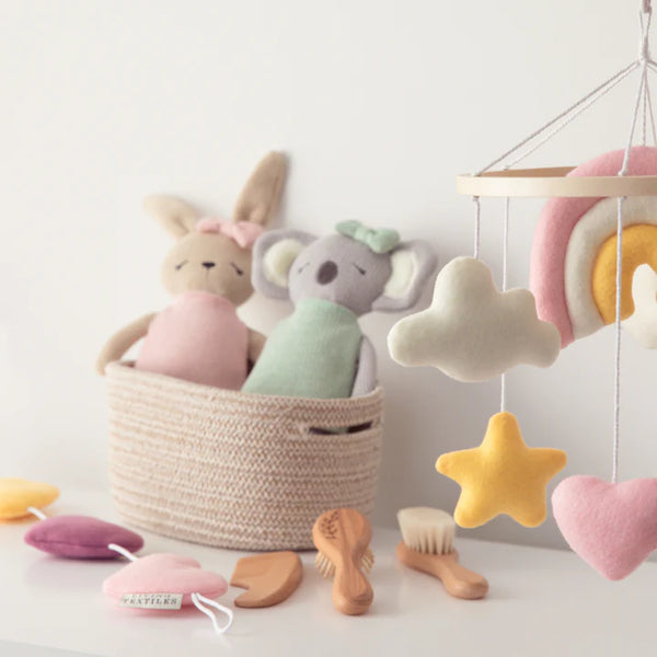 Pastel-colored plush toys and baby items on a light background