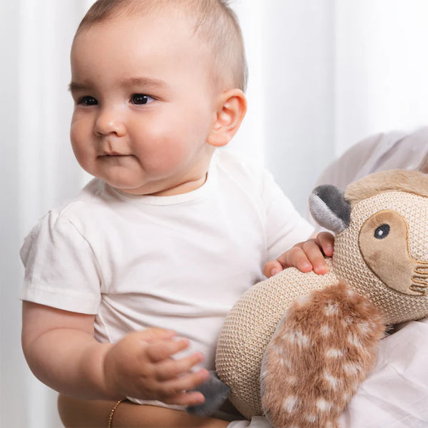 Baby holding a plush toy with a white background