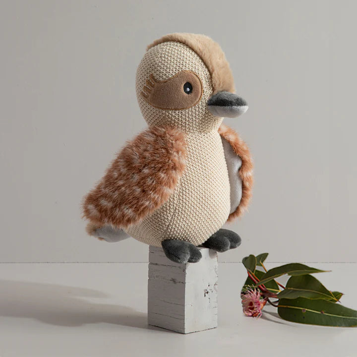 Knitted toy duck on a wooden block with a minimal background