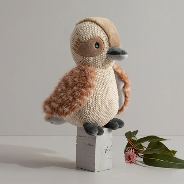 Knitted toy duck on a wooden block with a minimal background