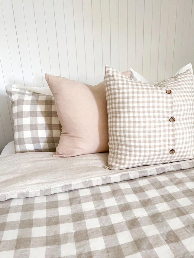 Checkered bedspread with pillows on a bed against a white paneled wall